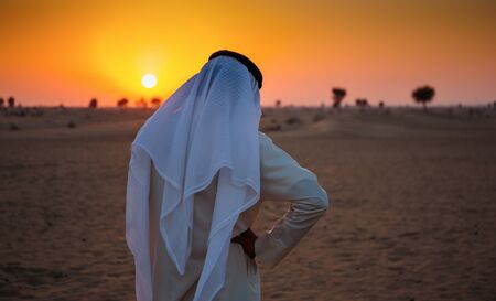 Arab man stands alone in the desert and watching the sunsetの写真素材