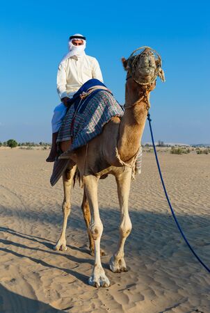 Arab man riding a camel in the desertの写真素材