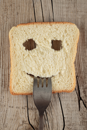 Happy toast with a fork in her mouth on a wooden board