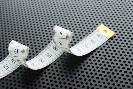 Curved white measuring tape on black background  perforated