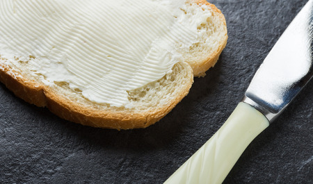 Sandwich, bread with butter and a knife on dark stone background