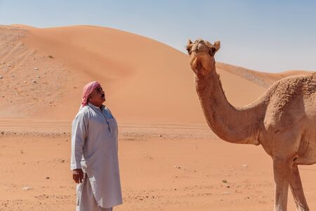 DUBAI, UAE - NOVEMBER 12, 2013: Arab man and camel in the desertのeditorial素材
