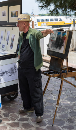 VENICE, ITALY - 26 JUNE, 2014: Artist sells paintings on the waterfront in Venice, Italyのeditorial素材