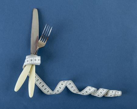 knife with a fork and measuring tape on a blue  backgroundの写真素材