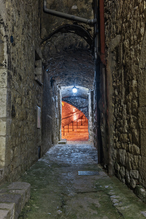 Narrow cobbled street in old town Peille at night, France.の写真素材