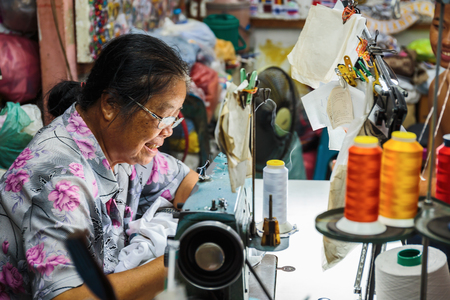 PATTAYA, THAILAND - APRIL 4, 2015: Old  woman sews on the sewing machine in the streetのeditorial素材
