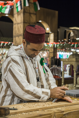 DUBAI, UAE - DECEMBER 4, 2017: Woodcarver artisan in national clothes in the pavilion of Turkey in Global Villageのeditorial素材