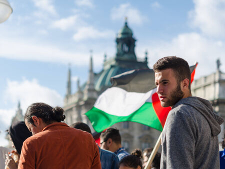 MUNICH, GERMANY - AUGUST 16, 2014: Face of a young activist on the background of the Palestinian flag. Pacific demonstration in support of the Gaza Strip population. For peace, freedom, independence and against a war.のeditorial素材