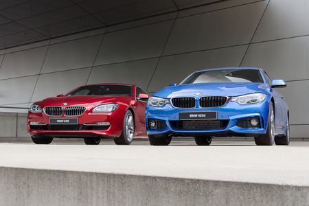 MUNICH, GERMANY - AUGUST 9, 2014: New modern models of executive business class BMW cars. Red 640i and blue 425d wet after rain autos.のeditorial素材