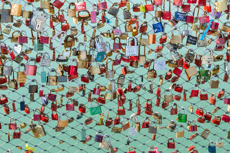 Newlyweds and lovers hang padlocks on the bridge over the river as a sign of love and fidelityの写真素材