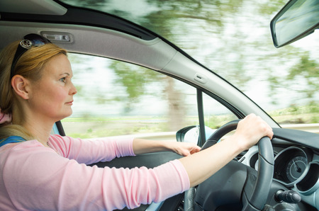 Profile portrait of serious calm woman careful and safe driving car on country road. Stock photo captured in active dynamic motion on high speed with slow shutter and blurred background.の写真素材