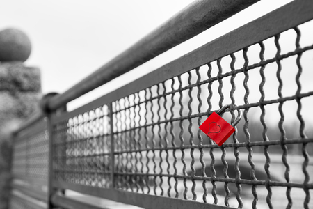 Red love lock padlock with heart on bridge symbol of true eternal love and commitment. Black and white stock photo with selective color effect.の写真素材