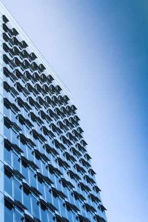 New modern high-rise steel and glass office building with large windows and open air conditioning ventilation system. Toned and filtered stock photo.の写真素材