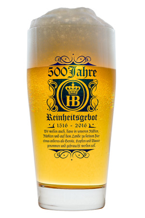 Munich, Germany - June 11, 2016: Glass of cold Bavarian beer with frothy foam head backlit isolated on white with text 500 years of Reinheitsgebot - German Beer Purity Lawのeditorial素材