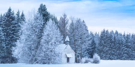 Christmas serene winter panoramic landscape with tiny woody chapel in snowy frozen forestの写真素材