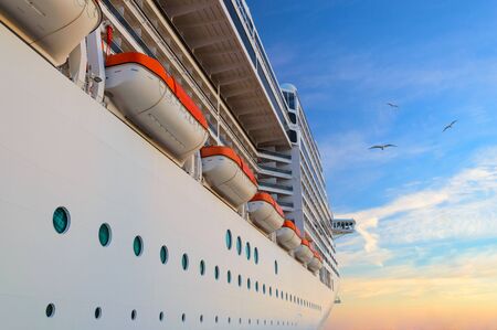 Luxury passenger ship cruise liner at sunrise with seagulls in dawn sky