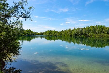 Forest lake in German national park with clear blue sky and trees reflection on water mirror surfaceの写真素材