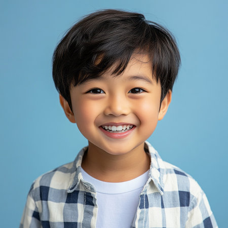 A cheerful Asian boy with a radiant smile, portrayed on a colorful plain backdrop, bringing youthful energy and positivity to commercial advertising visualsの素材