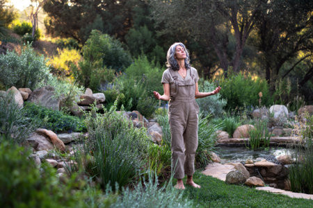 A woman stands peacefully in a lush garden, surrounded by vibrant greenery and blooming flowers during golden hour. She reflects thoughtfully, embodying serenity and connection with natureの素材