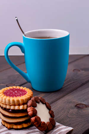 cookies with different fillings and a Cup of tea on a wooden tableの写真素材