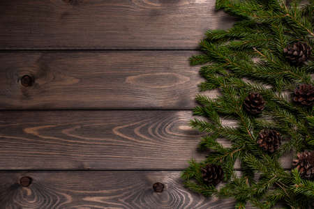 spruce branches and cones on a textured wooden table on the right with space to copyの写真素材