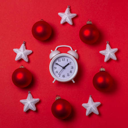 New year's circular composition of a clock in the center, snow-white stars and red balls on a red background. the view from the top.の写真素材
