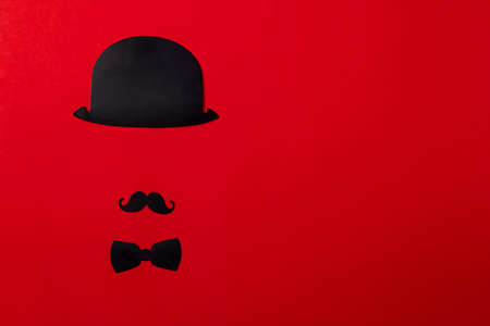 Stand of cardboard props mustache, hats, glasses, on a background of red textured paper.の写真素材