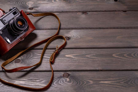 vintage camera in an old-fashioned brown retro leather case with a strap on a light brown table.の写真素材