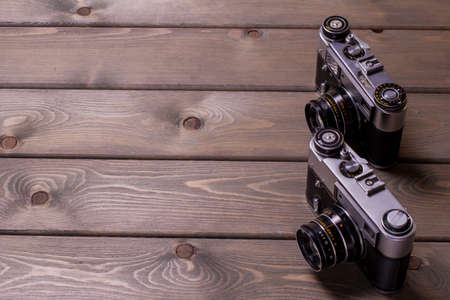 two vintage cameras stand against a background of brown wooden planks with space for copying. top viewの写真素材