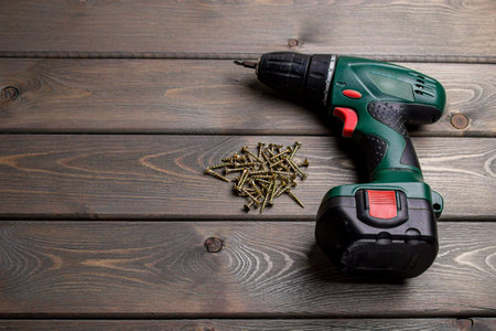 cordless screwdriver with self-tapping screws on a wooden background