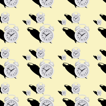 seamless pattern of a white alarm clock with a shadow on a yellow bed background.の写真素材