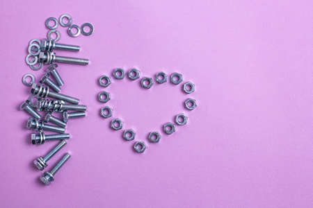 A heart made of metal nuts on a lilac paper background. Metal Heart for Valentine's Dayの写真素材