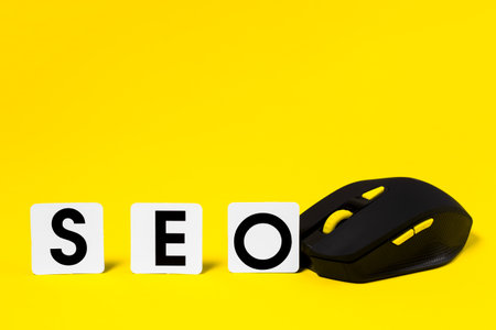 SEO, Search Engine optimization. SEO word on a card and a black computer mouse on a yellow background.の写真素材