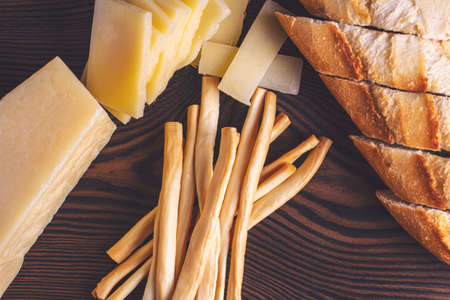 hard cheese and fibrous cheese with slices of bread are cut on a wooden boardの写真素材