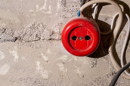 An old broken red electrical outlet on a brick wall with wires. Violation of electrical safetyの写真素材