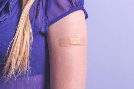 Female arm with adhesive bandage on blue background with copy spaceの写真素材