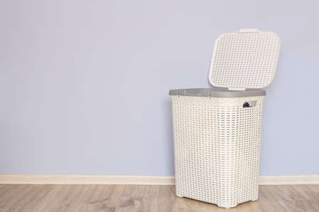 an open laundry basket with dirty laundry on floor against gray wallの写真素材