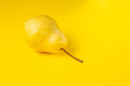 Yellow ripe juicy pear on a bright yellow background. Close-up side viewの写真素材