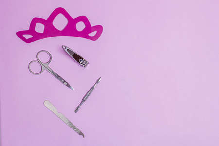accessories from a cosmetic set for nail care on a pink background with a crown for princesses. copy...