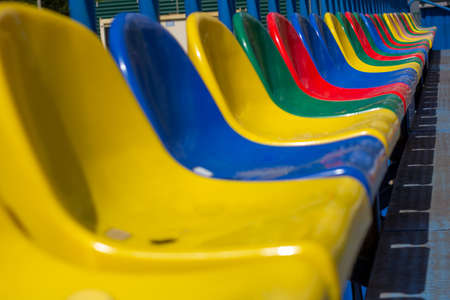 Empty stands, a grandstand with one row of plastic multi-colored seats, chairs for fans in a sports stadium. selected focusの写真素材