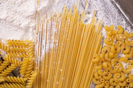 Top view of the Italian wheat pasta of three different types on the table with flour.Traditional recipe for spaghetti with noodles from Italyの写真素材