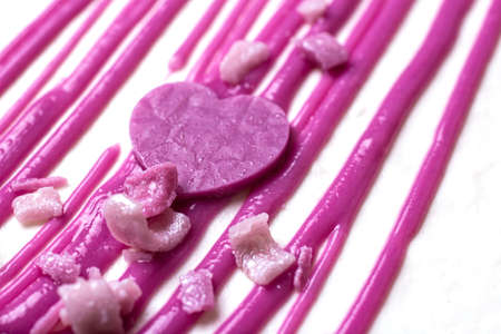 sweet pink decoration on a white cake close-up in the form of a heart and stripes. against the...