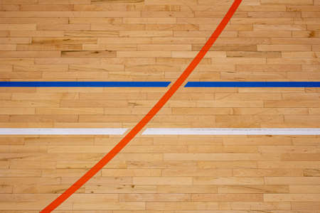 The worn wooden floor of the sports basketball hall with colorful marking lines and scratches from sneakersの写真素材