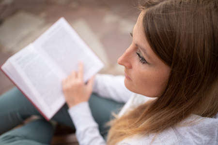 Top view of a woman reading a book. A young woman looks abstractedly to the side with an open book in her hands.の写真素材