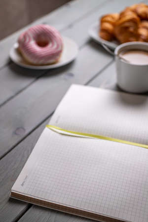 Coffee with milk, croissants and a notebook. Selective focus. The concept of morning planningの写真素材