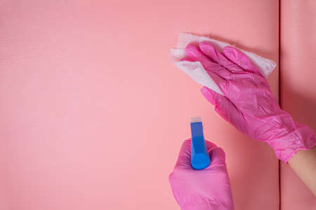 An employee in pink gloves disinfects the patient's couch with a disinfectant spray and a clean napkin. The staff cleans to prevent the spread of viruses and bacteria.の写真素材