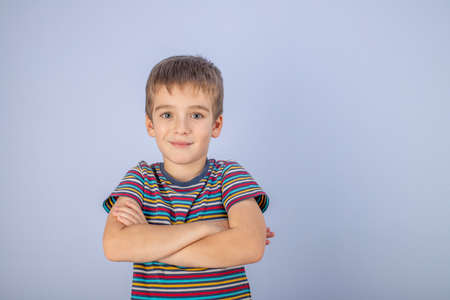 A little boy dressed in a multicolored striped T-shirt. Portrait of a beautiful teenage boy of early age. The pose of a happy smile.の写真素材