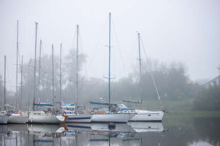 Yachts, sailing and fishing boats, small vessels moored to the pier in thick fog. Sights, old...
