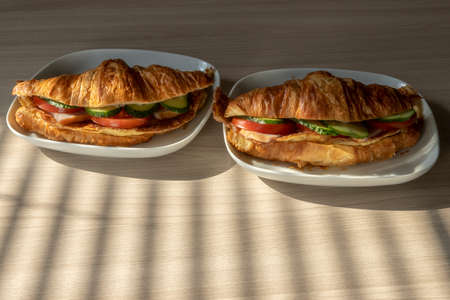 fresh croissants stuffed with omelet carbonade and fresh vegetables with cheese for breakfast under...