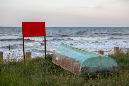 old boats at sunset on the seashore. a red warning sign with a place for text.の写真素材